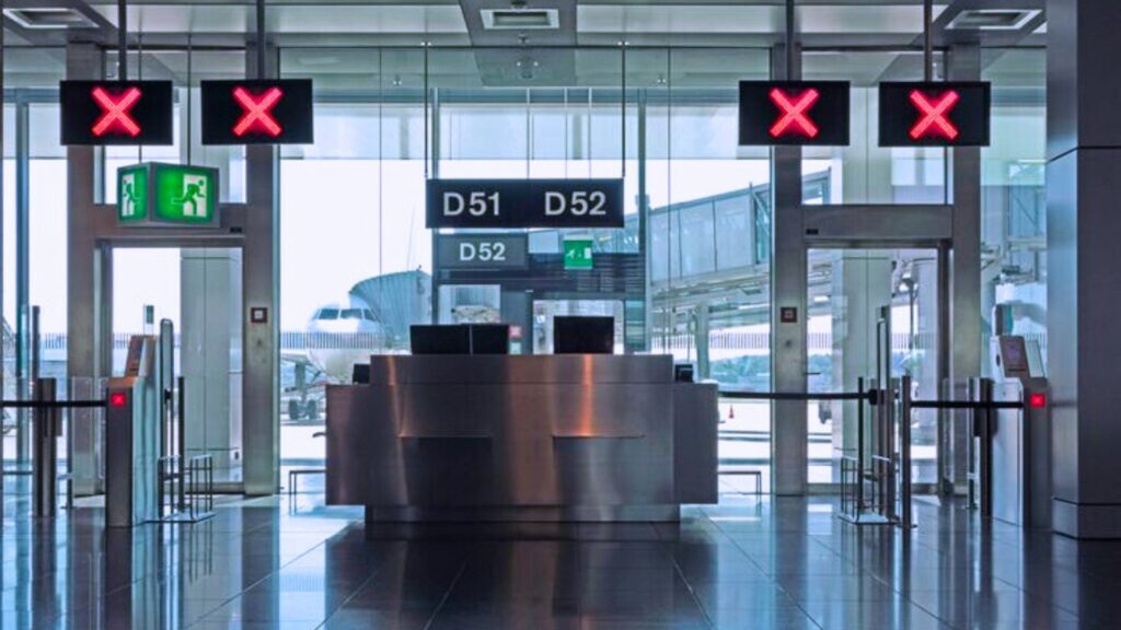 بوابات أمنية إلكترونية في مدخل منشأة حديثة مع إشارات ضوئية حمراء توضح إغلاق الممرات